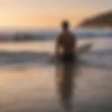 A surfer contemplating the waves at sunset