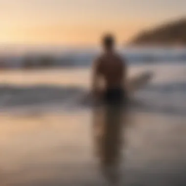 A surfer contemplating the waves at sunset