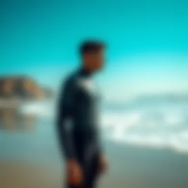 A tall individual suited up in a wetsuit on the beach